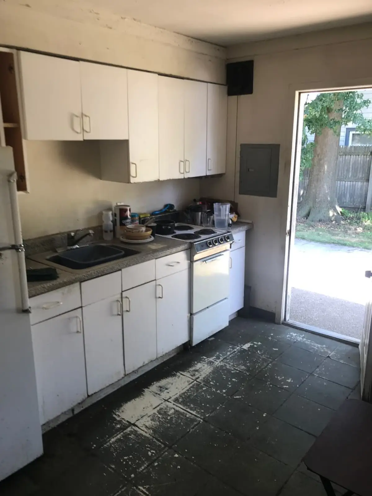 Selling a fire-damaged house in Levittown: galley kitchen with white cabinets and a stained floor