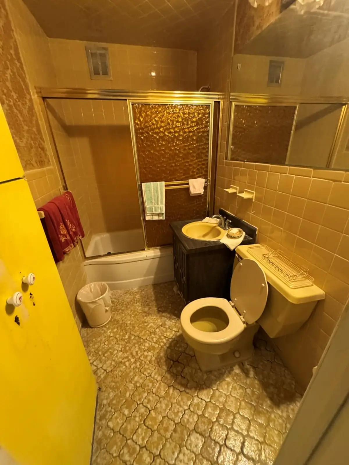 Downsizing or retiring in Levittown: gold-tiled bathroom with a glass shower door