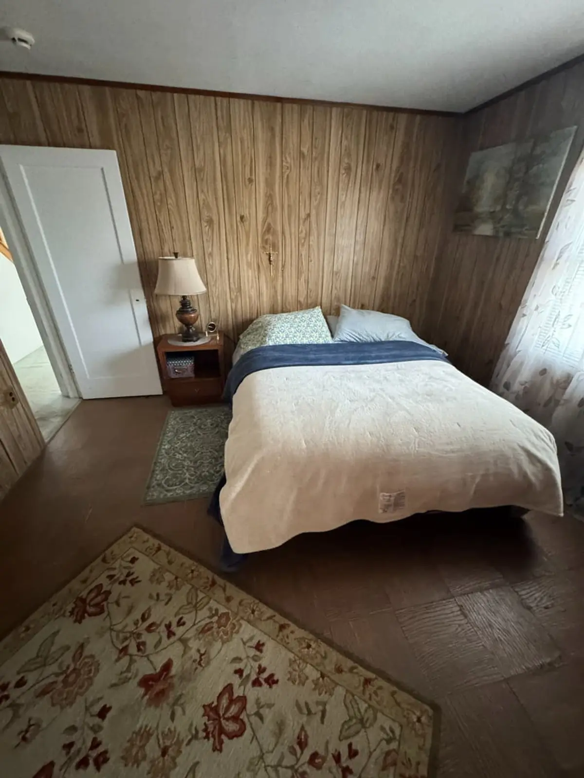 Selling estate property as an executor in Levittown: knotty-pine bedroom with a bed and nightstand