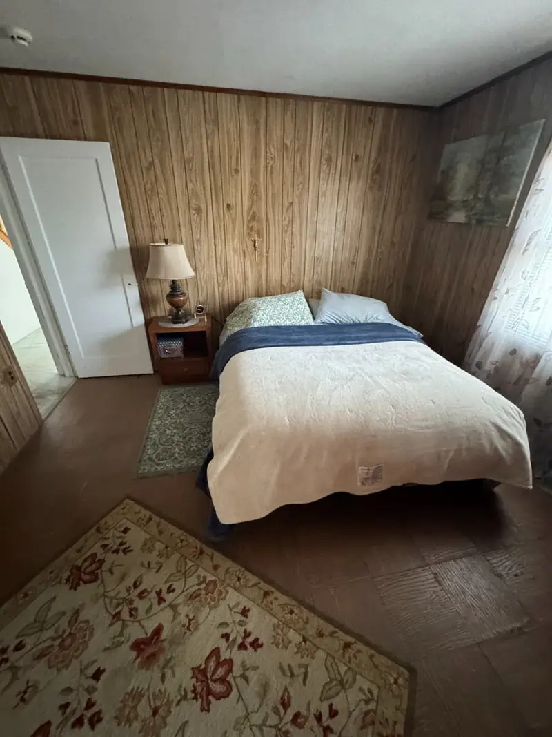 Knotty-pine bedroom with a bed and nightstand, Levittown, NY