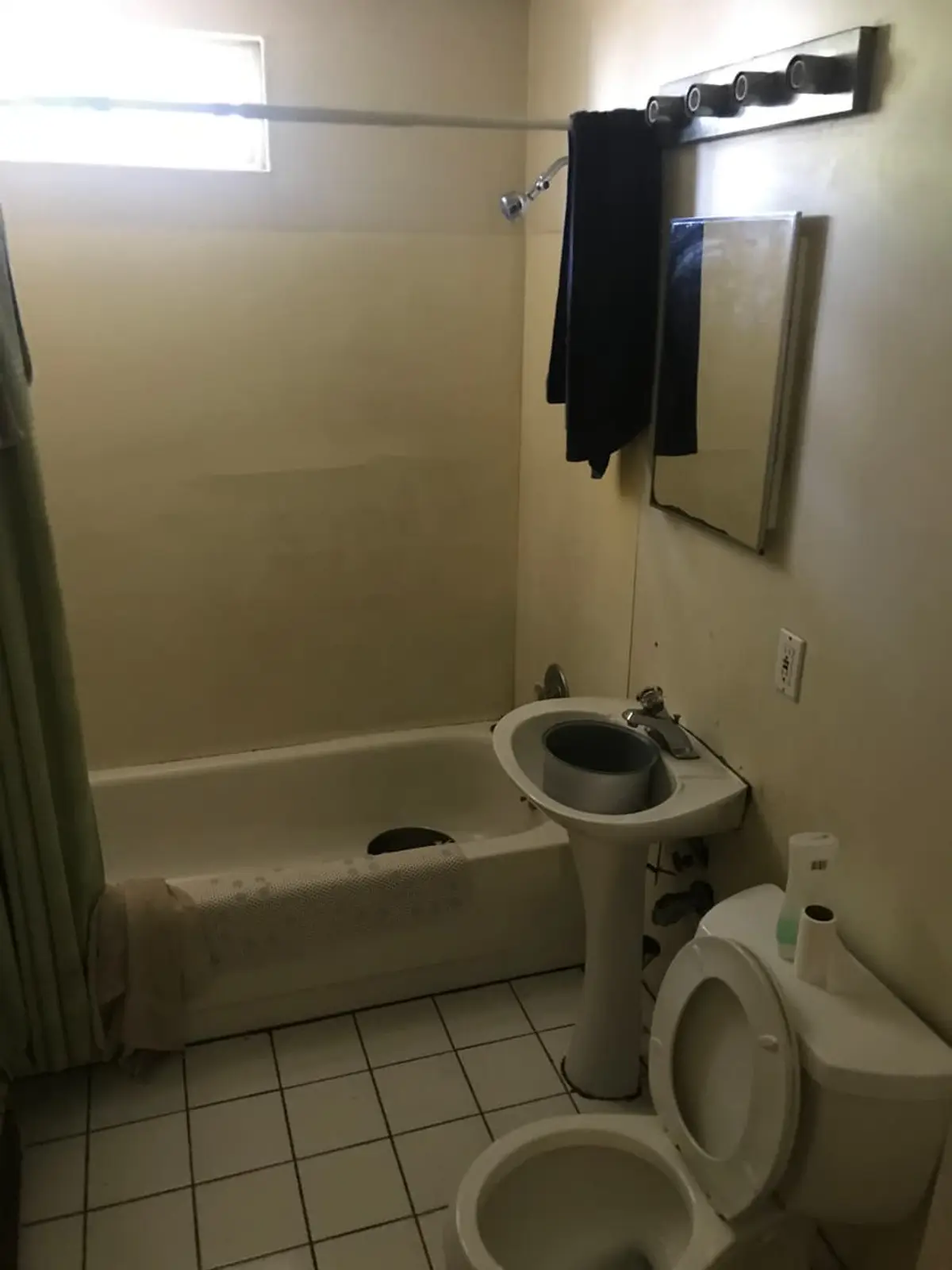 Selling a house with a lien in Levittown: plain bathroom with a pedestal sink and white tile floor