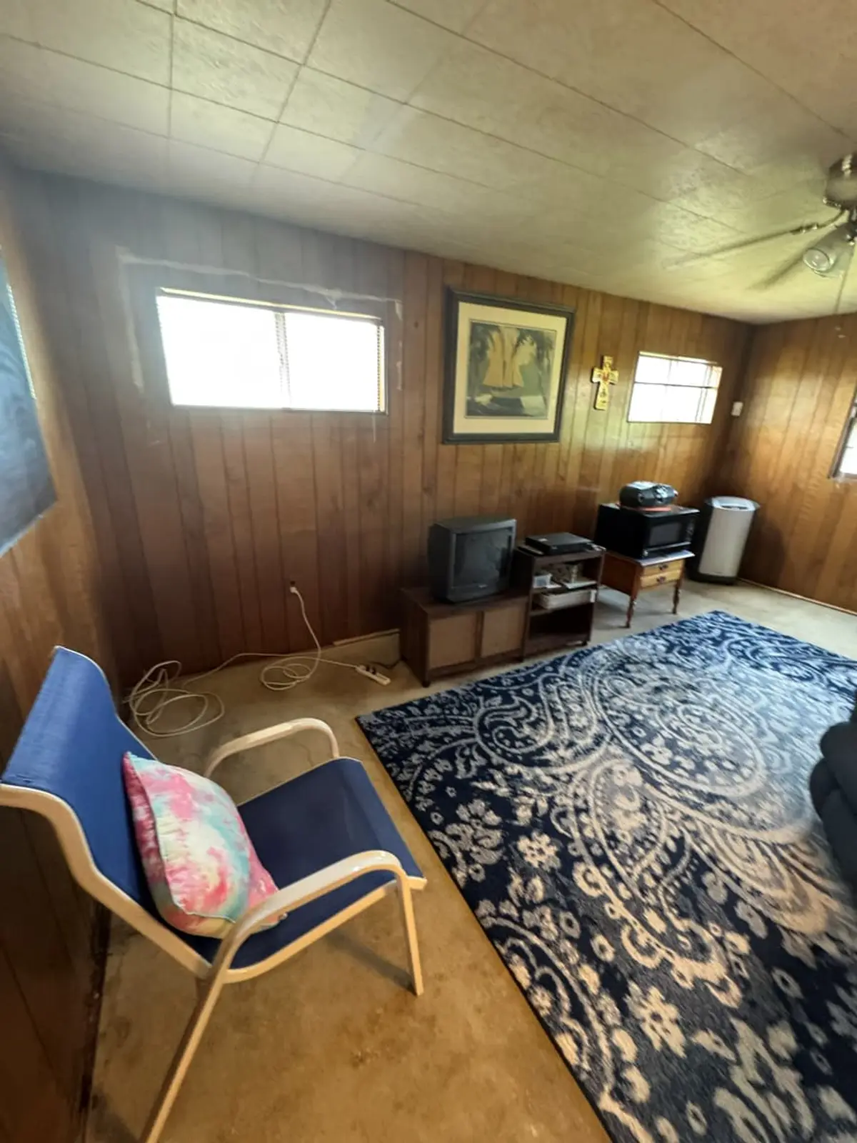Wondering if a cash offer on your Levittown house is legitimate: wood-paneled den with an old TV and a patterned rug