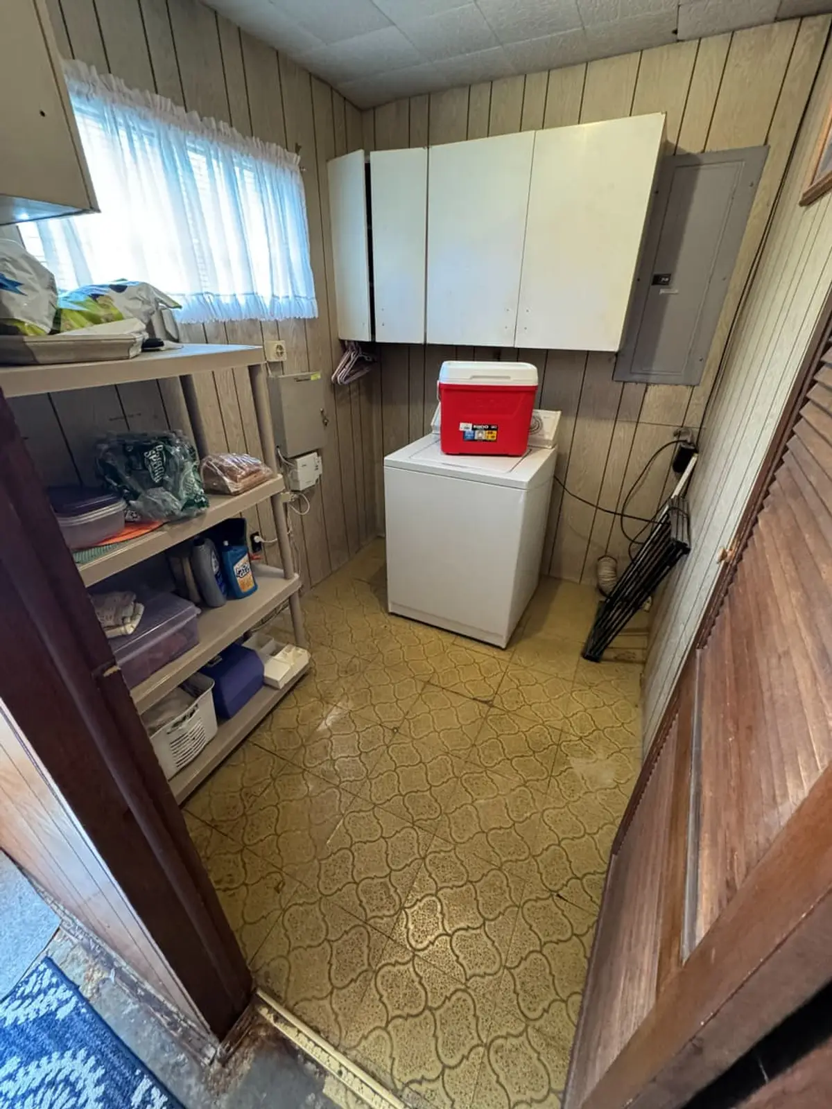 Selling a house in pre-foreclosure in Levittown: wood-paneled laundry room with a washer and shelves